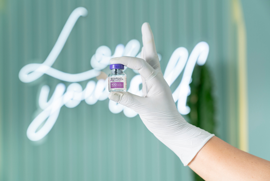 5 - RiKo Aesthetics A aesthetics practitioner's gloved hand with a bottle of Botox